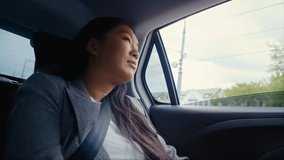 Business Chinese woman driving in a taxi and using earphones. Shot with RED helium camera in 8K. 