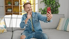 Young caucasian man having video call sitting on sofa at home