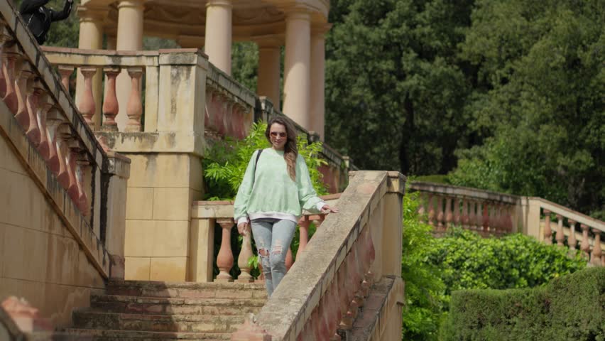 The girl walks in the park, goes down the stairs