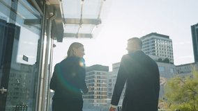 Back view following two business partners man woman walking along terrace office building roof overlooking modern city skyscrapers, discuss work exchanging smiles and positive vibes in sunshine rays - Powered by Shutterstock - Get 15% off with code: PIKWIZARD15