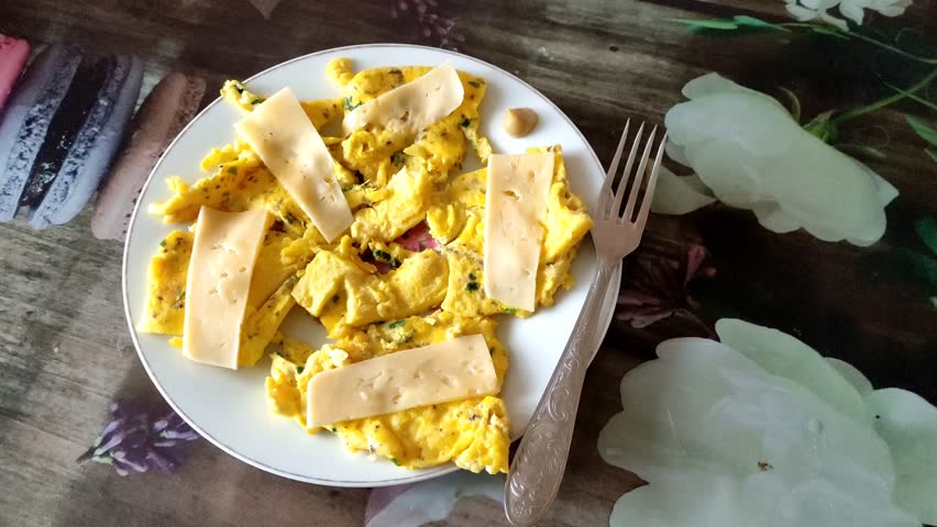 Omelet or scrambled egg with a cheese and herbs on the plate