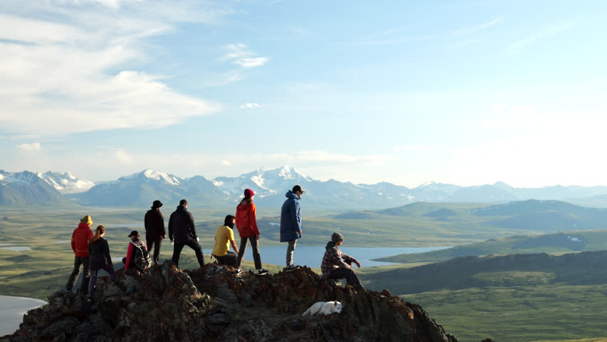 Traveling group together raise arms and joy achievement on mountain top. Happy hikers celebrate high win, success on cliff peak at scenic landscape view Royalty-Free Stock Footage #1107181231