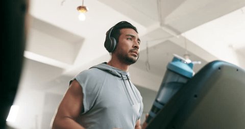 Fitness, watch and man on a treadmill with headphones at gym training for exercise. Profile of Asian athlete person listening to music for running, cardio time or workout on machine for health – Stockvideo