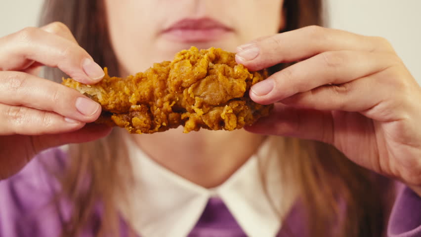 Young woman eating chicken fat leg and burger student eat junk food delivery close up.