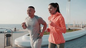 Smiling multicultural couple jogging by sea at dawn - Powered by Shutterstock - Get 15% off with code: PIKWIZARD15