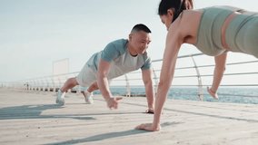 Handsome multinational couple doing push ups by sea at dawn - Powered by Shutterstock - Get 15% off with code: PIKWIZARD15