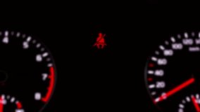 Intentionally blurred clip of a blinking flashing seatbelt warning icon, at the center of a modern car's dashboard, small and far.
