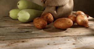Raw potatoes with zucchini and onions on wood. A new crop of vegetables in a burlap bag. Rustic food. Dolly shot. High quality 4k footage.