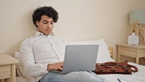 Young latin man business worker using laptop sitting on bed at hotel room - Powered by Shutterstock - Get 15% off with code: PIKWIZARD15