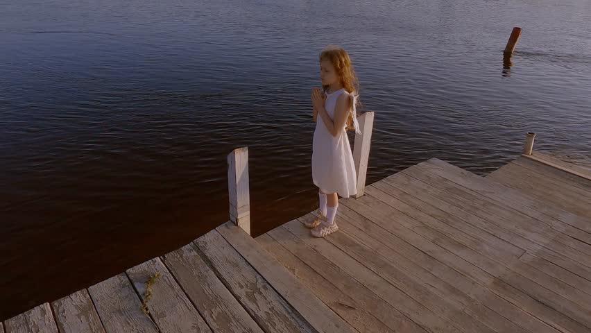 Cute little angel girl with wings near the water and is romantically bored.