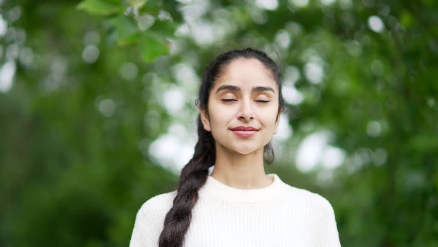Young indian woman enjoying nature taking deep breaths of fresh air standing among trees in forest or park. Outdoors closing Female girl Inhaling and Exhaling her eyes calm rest and stress relief Royalty-Free Stock Footage #1107213569