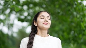 Young indian woman enjoying nature taking deep breaths of fresh air standing among trees in forest or park. Outdoors closing Female girl Inhaling and Exhaling her eyes calm rest and stress relief - Powered by Shutterstock - Get 15% off with code: PIKWIZARD15