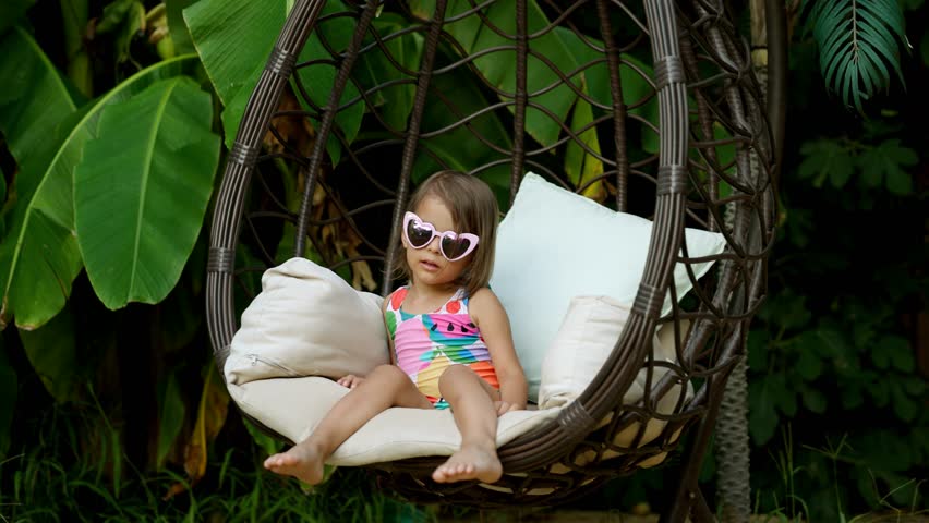 Funny cute girl on summer vacation. The child has fun on the beach. Cute baby girl in a colorful swimsuit and sunglasses is resting. Royalty-Free Stock Footage #1107214665