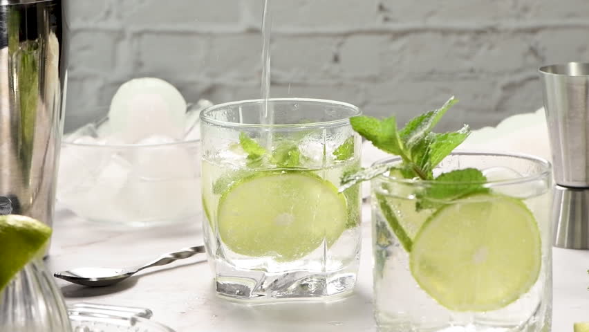 Mint mojito is the perfect non-alcoholic recipe. A glass with ice, lime and mint is filled with tonic. Close-up. This is one part of a series of vertical videos. Super slow motion Royalty-Free Stock Footage #1107218085