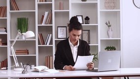 African American girl reads documents and rejoices, happiness, she won money, tender. Her company receives new funding. Hispanic latin business lady in black jacket works freelance on a laptop 