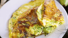 Fried omelet with zucchini,in a plate on a wooden table.