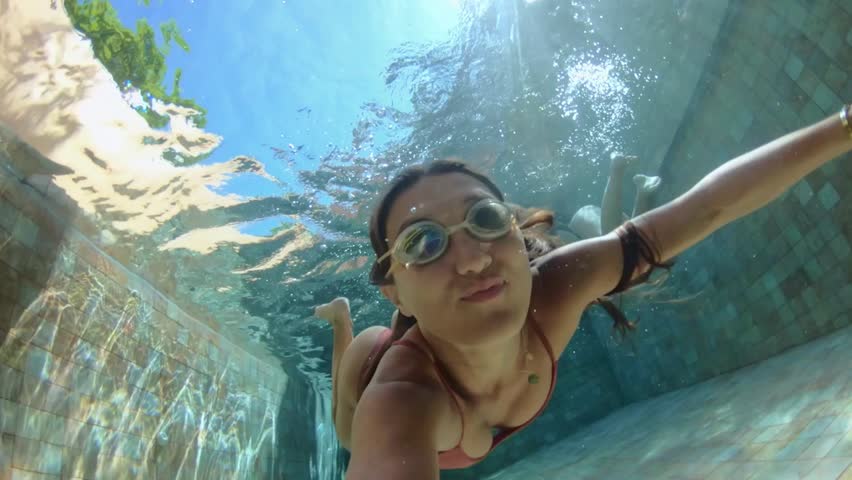 Self Portpait. Active young woman jump and dive underwater in a blue swimming pool. Travel lifestyle, water sport, snorkeling adventure. Summer sea beach vacation . Young female swimmer shooting
