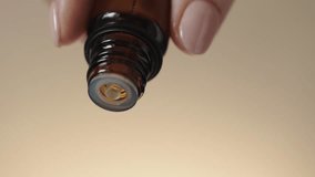 Essential oil droppind from dark glass cosmetic bottle, selective focus, macro