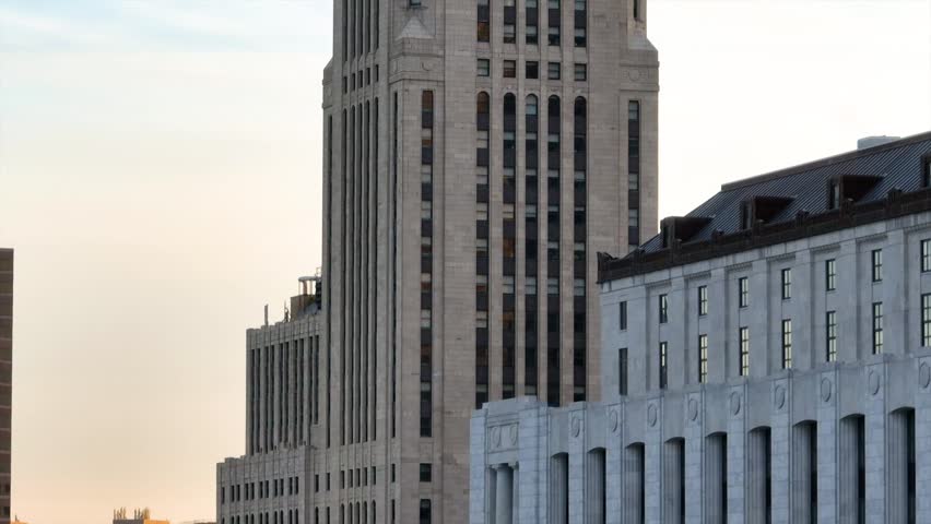 Aerial video with birds flying past illuminated LeVeque Tower at sunrise with exterior lights on