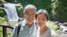 slow motion old asian couple smiling happily in front of the waterfall - Powered by Shutterstock - Get 15% off with code: PIKWIZARD15