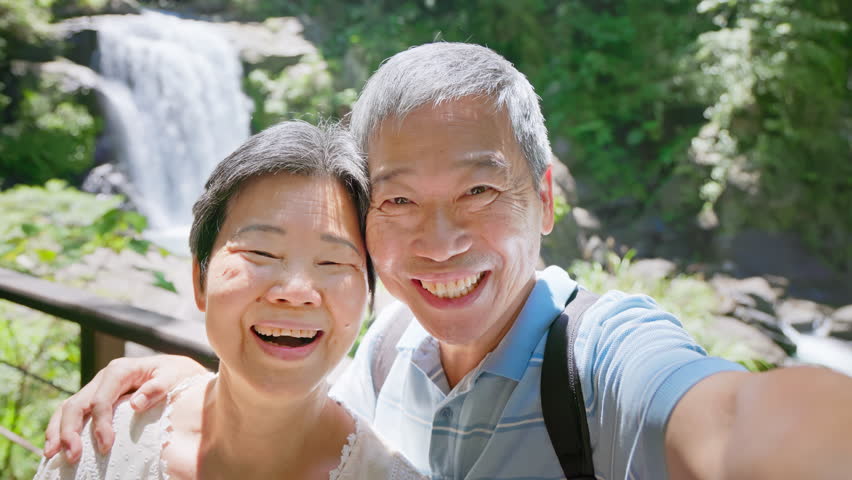 Old couple video chatting in front of the waterfall | Shutterstock HD Video #1107234277