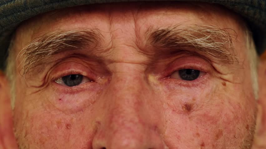 Tired eyes of a senior caucasian man. Close-up of an elderly wrinkled man's eyes. Wise look of an old grandfather. Grandparents day concept. Royalty-Free Stock Footage #1107236435