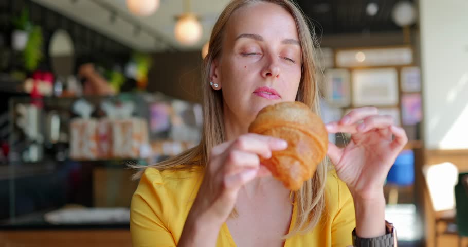 Young woman with bang eating croissants at cafe Royalty-Free Stock Footage #1107242107