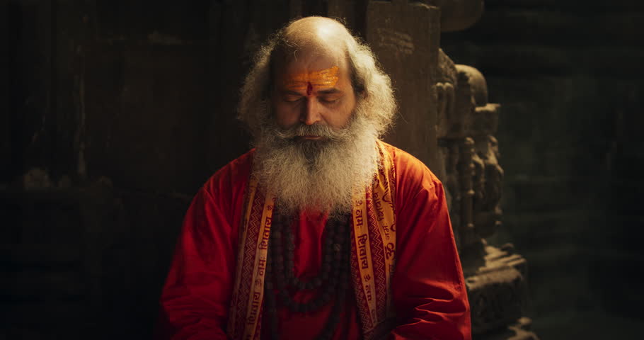 Zoom in Portrait of a Senior Hindu Monk Looking at the Camera and Smiling in an Ancient Temple. Friendly Indian Senior Man Posing as he is seeking Guidance and Wisdom from his Religion Royalty-Free Stock Footage #1107248023