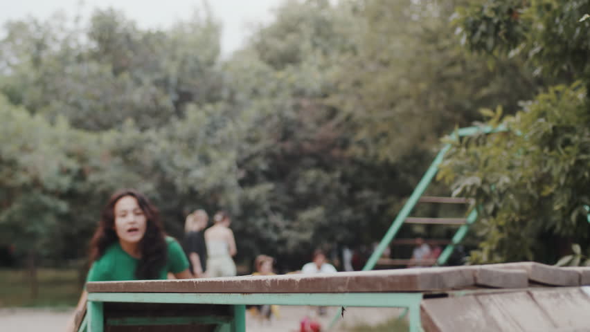 Young female dog owner leading quickly the big black dog over the overpass on a leash and talking with it on an outdoor dog training ground. Concept of proper pet care and handling
