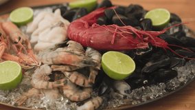 Close up footage of a variety of fresh Seafood on the plate with ice, lobsters, shrimps, cuttlefish, shells. serving in a restaurant