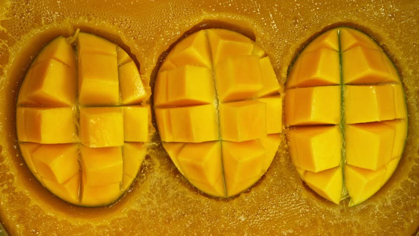 Fresh sliced mangos falling into juice, super slow motion filmed on high speed cinematic camera at 1000 fps.
