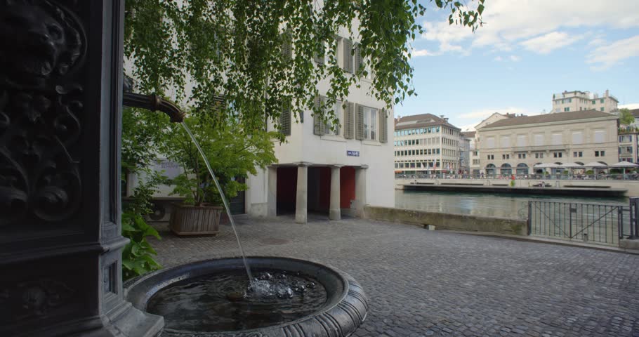 Old public drinking water fountain in downtown Zurich city, Switzerland. Sunny summer day, wide-angle view, real time, no people