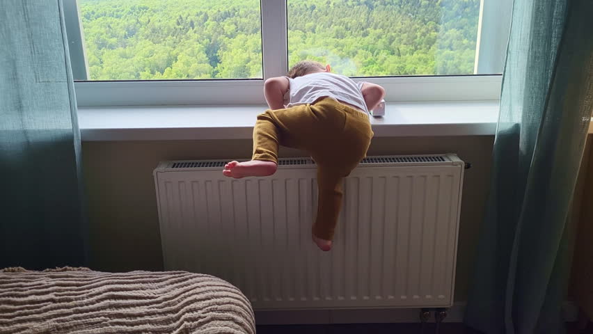 The child climbs on the window sill. Toddler baby climbs dangerously on the window. Kid boy aged two years (two-year-old) Royalty-Free Stock Footage #1107260219