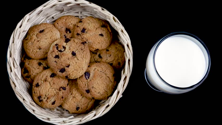 Fresh Milk and Chocolate chip cookies in a bamboo basket isolated on black background