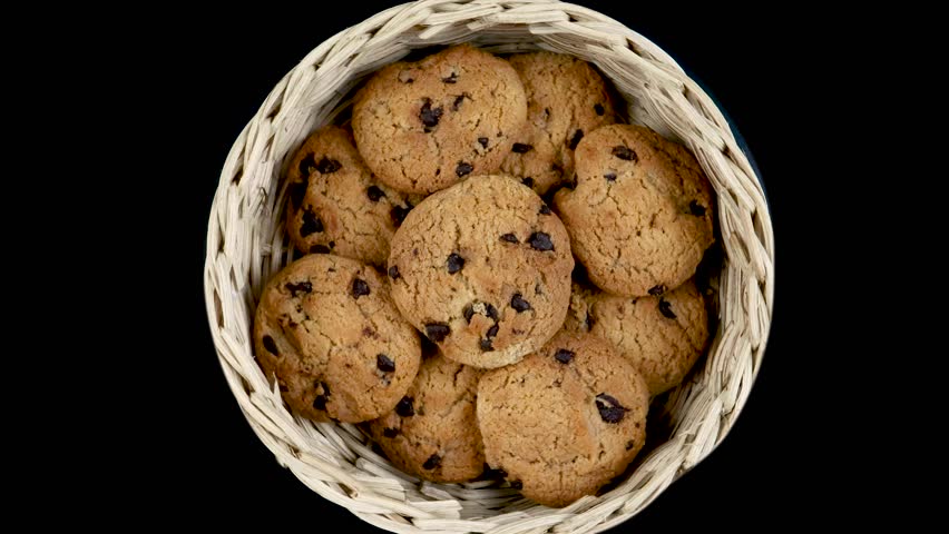 Chocolate chip cookies in a bamboo basket isolated on black background