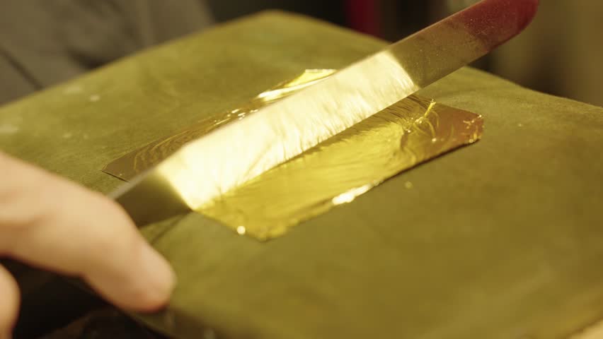 The artist cuts gold leaf into pieces to apply to the oil painting Royalty-Free Stock Footage #1107262849