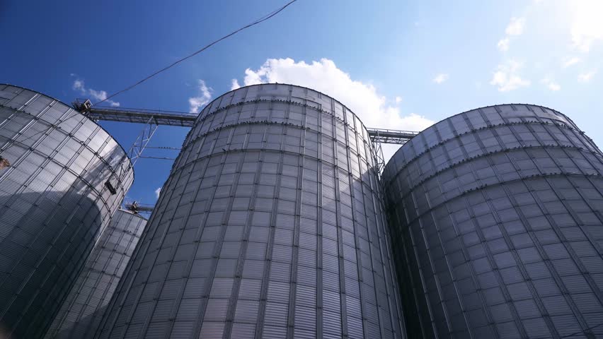 Modern grain elevator terminal in a sea port. Metal tanks and conveyors of grain-drying, handling complex silos in seaport. Wheat loading, shipment and transportation facility. Royalty-Free Stock Footage #1107262863