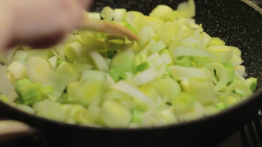the stove is turned on, the oil and chopped leeks are put in the pan