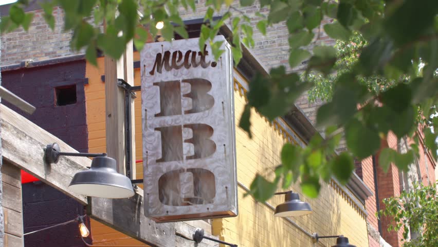 Meat BBQ restaurant sign in Lansing, Michigan Old Town district with stable establishing shot.