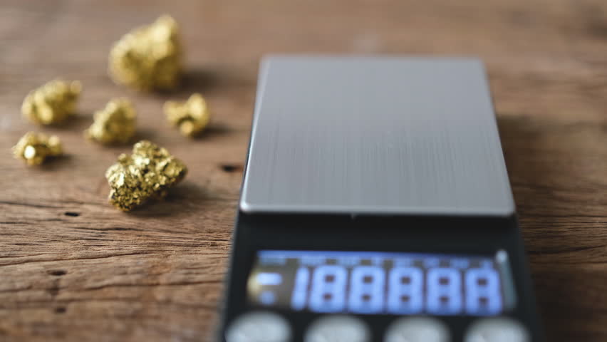 man's hand is placing a standard calibration weight on a weighing scale.