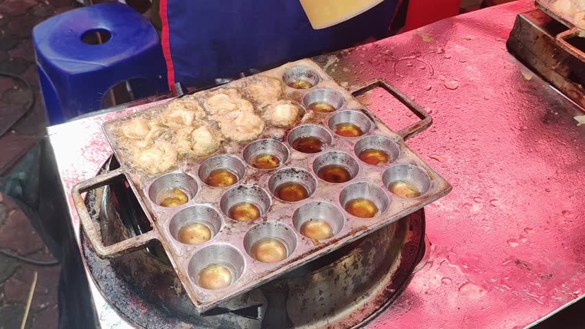 Video of the seller frying beef meatballs which are smeared with egg and fried in a mold pan | Shutterstock HD Video #1107277369