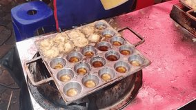 video of the seller frying beef meatballs which are smeared with egg and fried in a mold pan