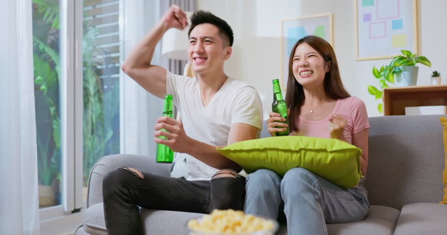 Asian couple watching soccer game together with joy and excitement they are drinking beer in summer | Shutterstock HD Video #1107279133