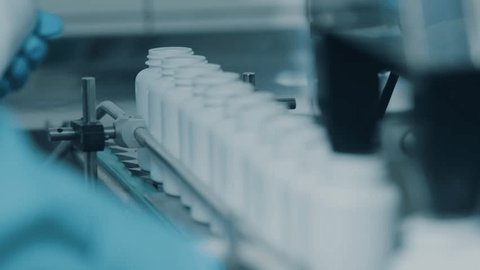 4K conveyor with moving empty white plastic tubes on the production line and filling with capsules. Automatic machine in the factory. Modern High-Tech Pharmacology Factory. Close Up, DOF 库存视频