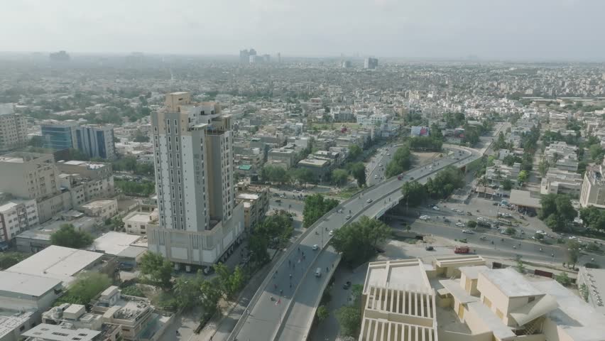 Aerial drone shot from right to left of traffic movement over Shahrah e qaideen road, Karachi Metropolitan city in Pakistan on a sunny day.