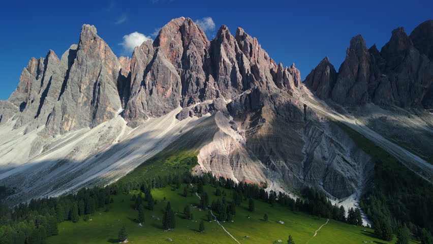 Beautiful drone footage view of a large and beautiful mountain ridge with blue sky and green meadows. Panorama of mountain peaks, Dolomites, Italy
 Royalty-Free Stock Footage #1107290581