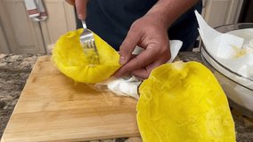 The top down view of a man scraping the flesh out of the spaghetti squash.