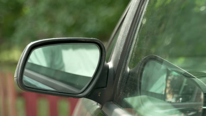 automotive theme green not very clean car the driver gets behind the wheel and adjusts the mirrors, opens the window and looks in the mirror and smiles with satisfaction Royalty-Free Stock Footage #1107293585