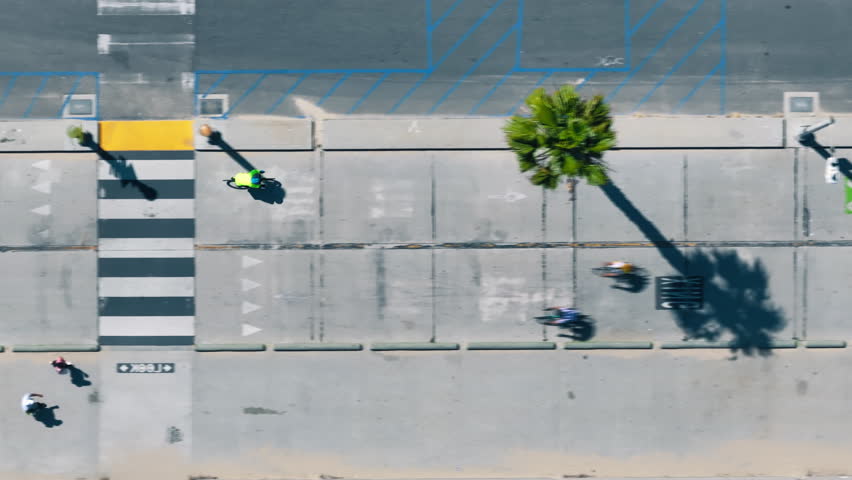 Top view of active man riding bicycle on the road, Santa Monica, Los Angeles, California, USA. Aerial view of cyclist training on the street. Drone shot of pedestrians walking on sidewalk, 4k footage Royalty-Free Stock Footage #1107298083