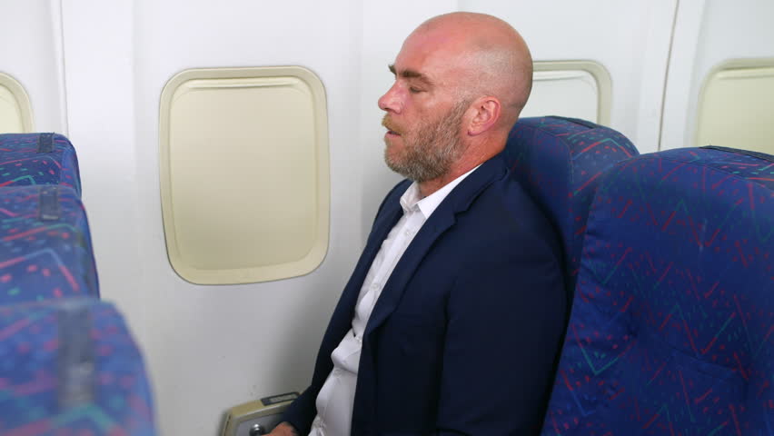 A nervous man with a beard taking deep breaths trying not to panic with anxiety on a passenger plane airliner airplane Royalty-Free Stock Footage #1107298207
